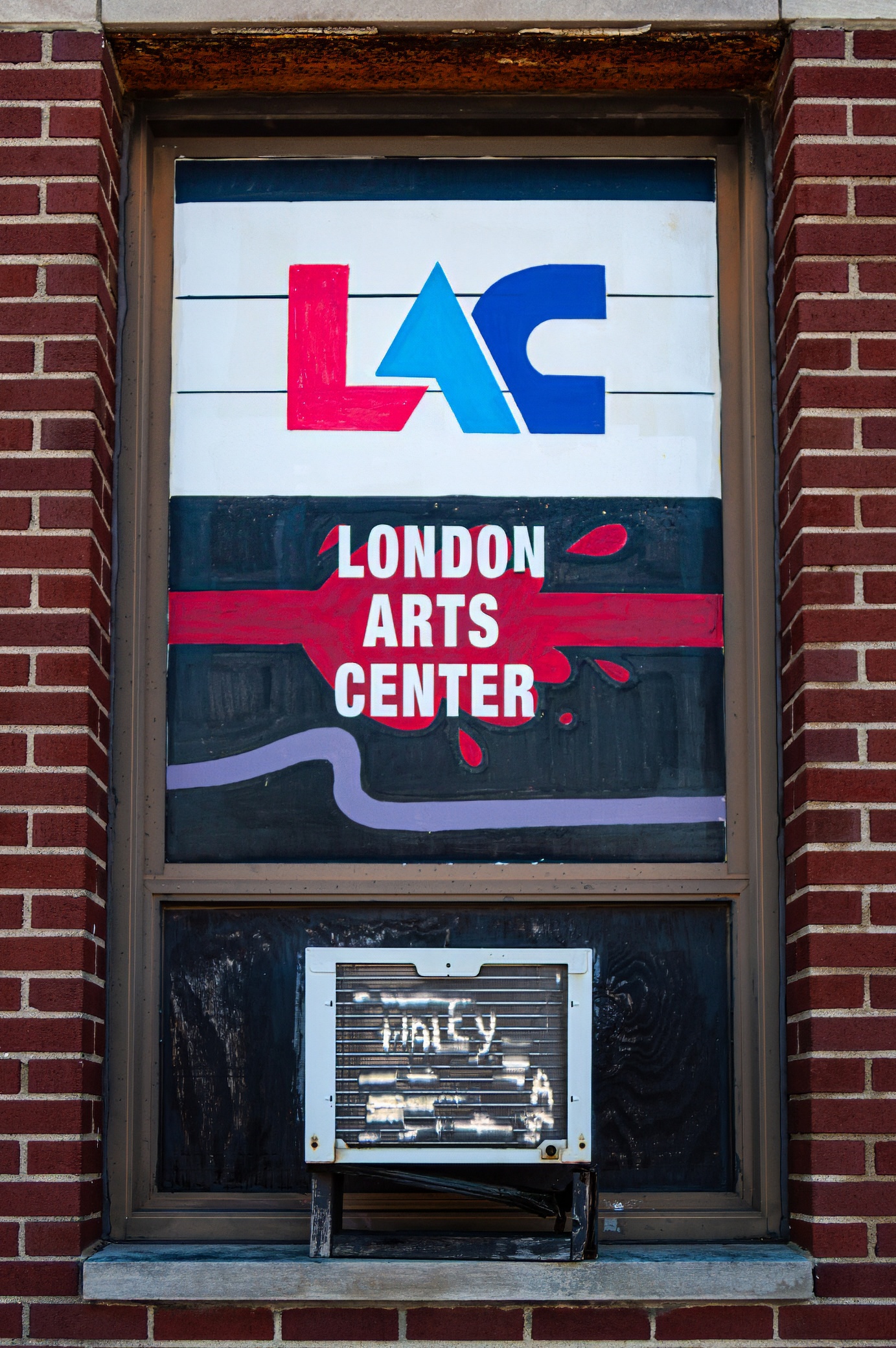 Sign for the London Arts Center displayed in a window, with the abbreviation LAC at the top and the name prominently featured below.