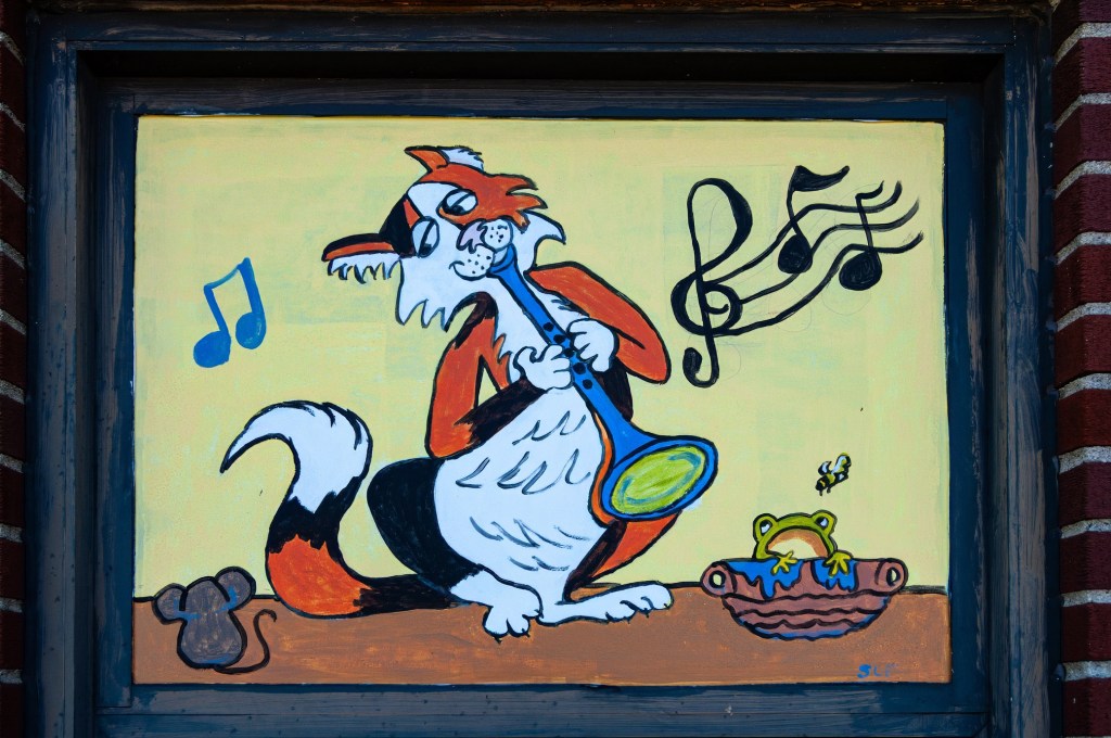A colorful mural depicting a cartoon fox playing a blue clarinet, surrounded by musical notes, a mouse, and a frog sitting in a basket.
